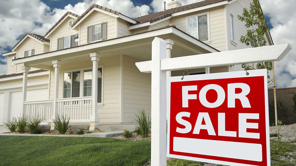 Image of For Sale sign in the yard of a suburban house