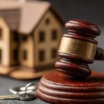 Rent control image of judges gavel in front of model house and keys