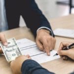 Image of a cash security deposit in California as a female tenant signs a lease agreement