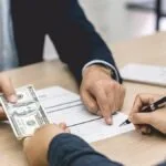 Image of a cash security deposit in California as a female tenant signs a lease agreement