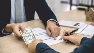 Image of a cash security deposit in California as a female tenant signs a lease agreement