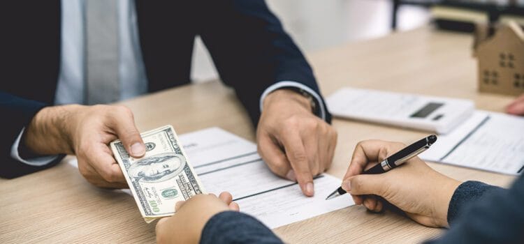 California Security Deposit Return Image of a cash security deposit in California as a female tenant signs a lease agreement