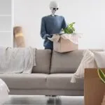 Human skeleton model with cardboard box near sofa in living room on moving day - spooky move ins