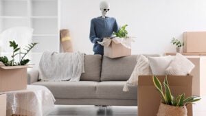 Human skeleton model with cardboard box near sofa in living room on moving day - spooky move ins